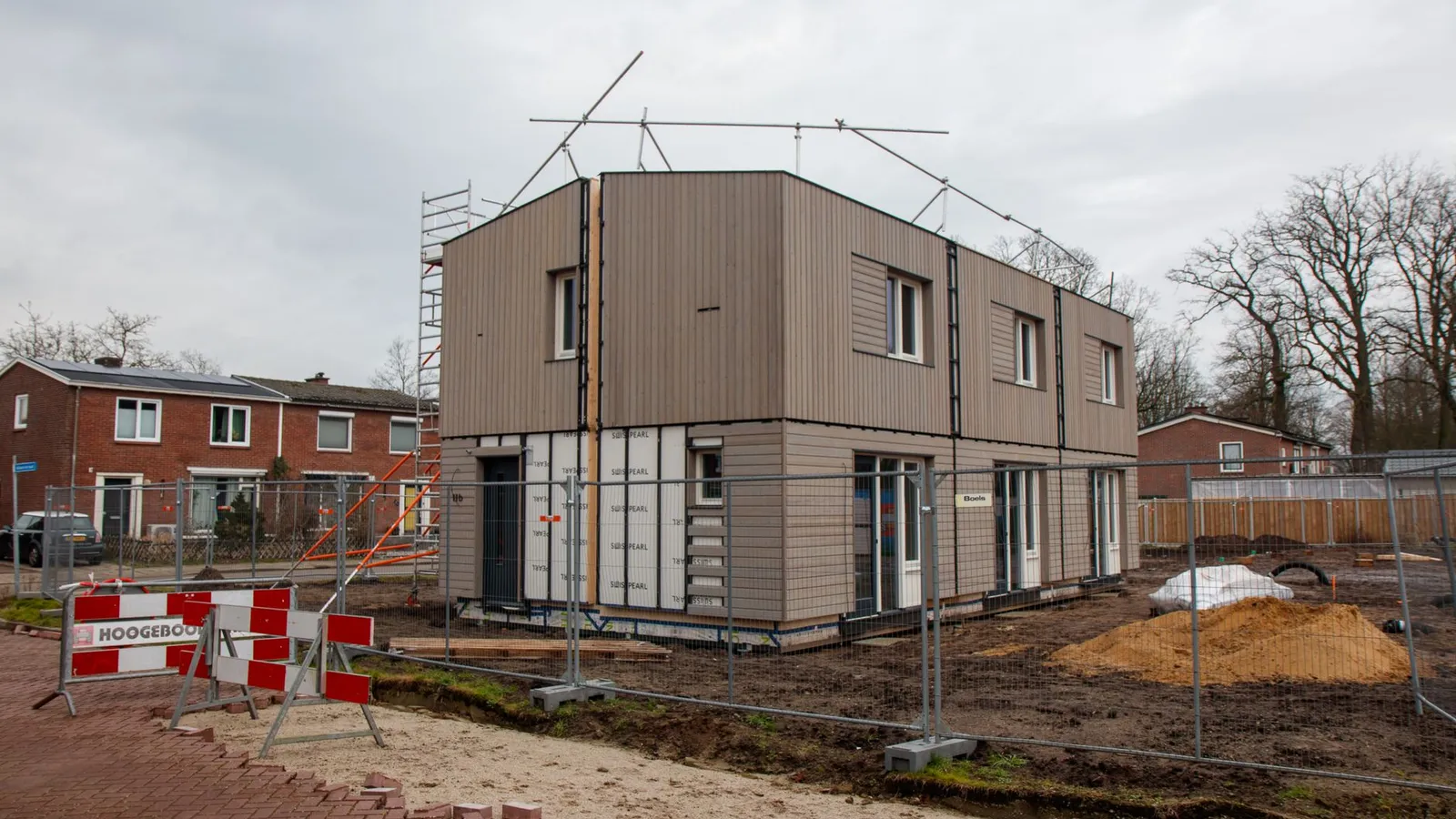 Moderne nieuwbouwwoning in aanbouw met steigers en bouwhekken